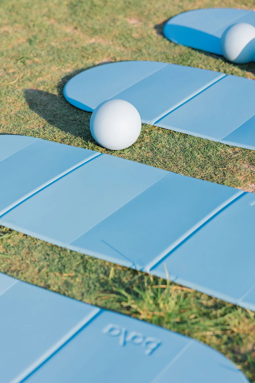 Blue mats and pilates balls set up on the grass before class