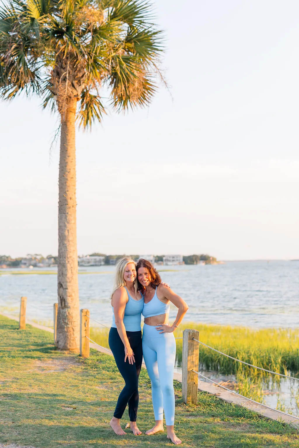The two Coastal Sculpt founders embracing beneath a palmetto tree by the water